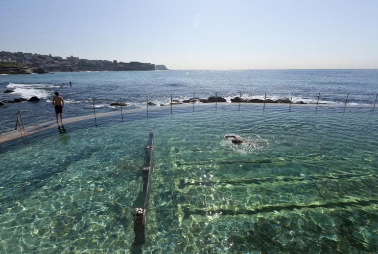 Bronte Baths with ocean waves swirling against the rocks surrounding the pool, Bronte Beach, Sydney, New South Wales © Tourism AustraliaStairs leading down to the calm, clear water of  Bronte Baths as the sunsets over the ocean, Bronte Beach, Sydney, New South Wales © Destination NSWA public seating area above the calm waters of Bronte Baths beneath a purple sky during sunset at Bronte Beach, Sydney, New South Wales © Destination NSWAerial view over people swimming at Bronte Baths with ocean waves crashing around its edge at Bronte Beach, Sydney, New South Wales © Ashlea WheelerA person swimming in the sparkling water of Bronte Baths with another person standing on the edge overlooking the ocean at Bronte Beach, Sydney, New South Wales © Andrew Gregory/Destination NSW   Bronte Baths, Bronte Beach, Sydney, New South Wales © Tourism Australia   Bronte Baths, Bronte Beach, Sydney, New South Wales © Destination NSW   Bronte Baths, Bronte Beach, Sydney, New South Wales © Destination NSW   Bronte Baths, Bronte Beach, Sydney, New South Wales © Ashlea Wheeler  